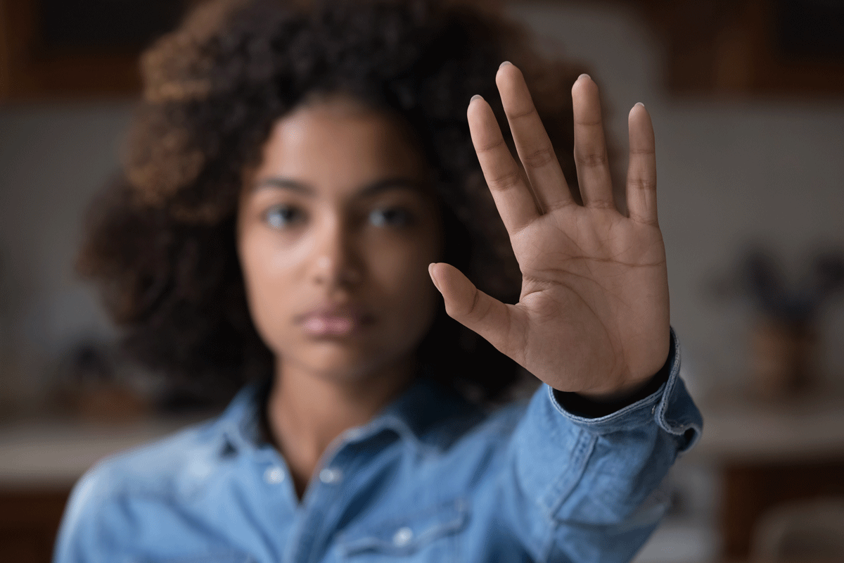 Frau hält Hand vors Gesicht und macht Stopp-Geste