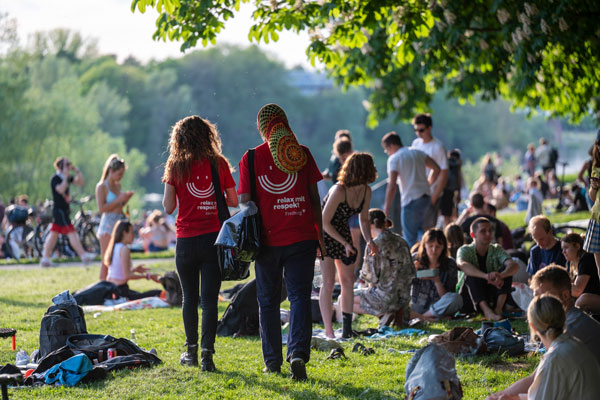 Viele Personen in einem Park, zwei Nachtmediator*innen laufen durch die Menge