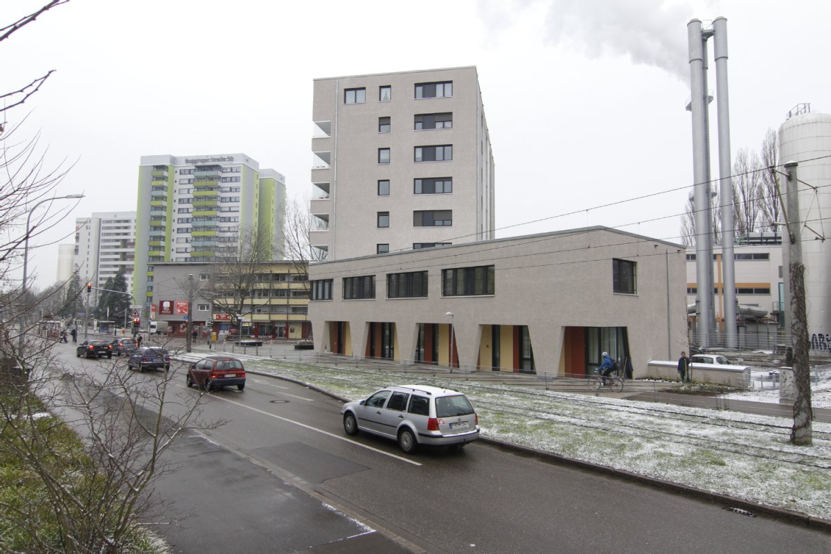 Die wenig befahrene Straße "Binzengrün" bei trübem Wetter, im Hintergrund sind Gebäude der Bugginger Straße zu sehen.