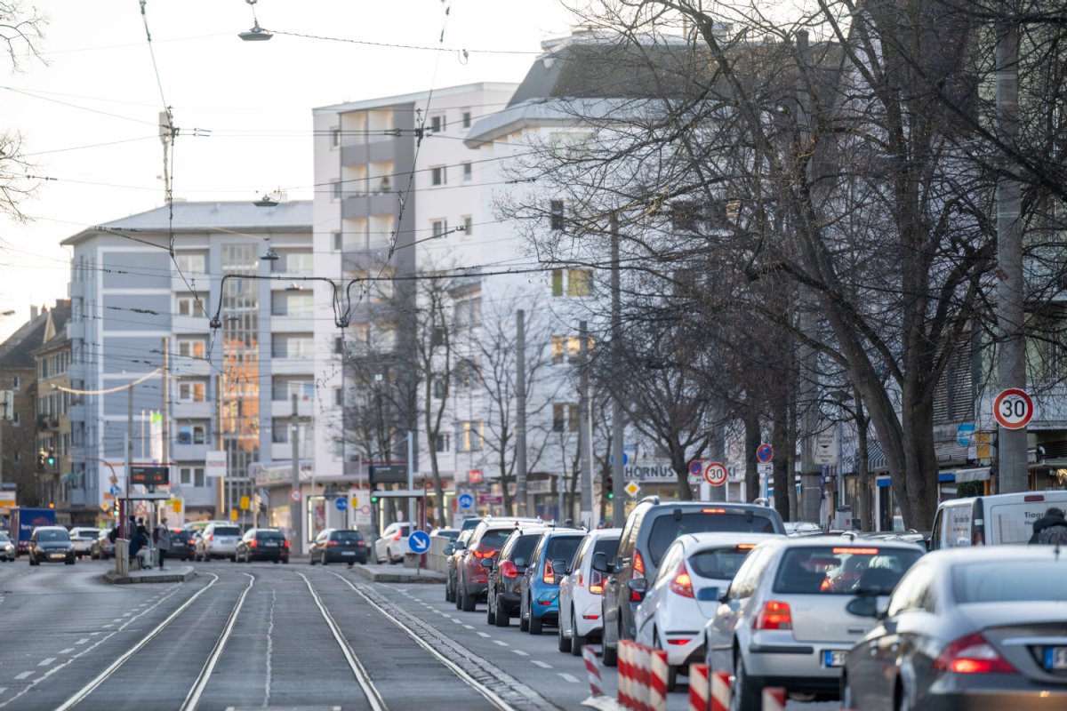 Die Zähringer Straße in Freiburg. Autos stehen auf der rechten Seite im Stau, rechts daneben parkende Autos. im Hintergrund Mehfamilienhäuser.