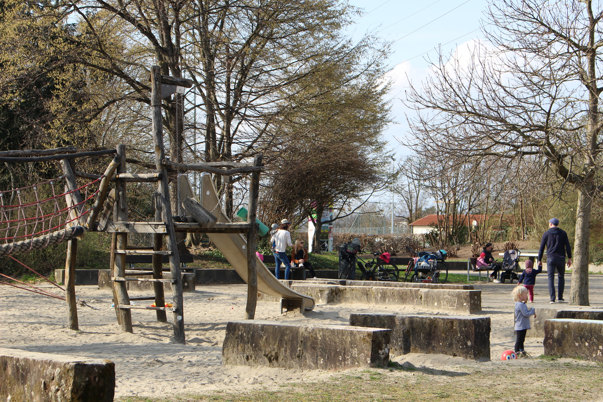 Belebter Spielplatz mit Rutsche und Hängebrücke