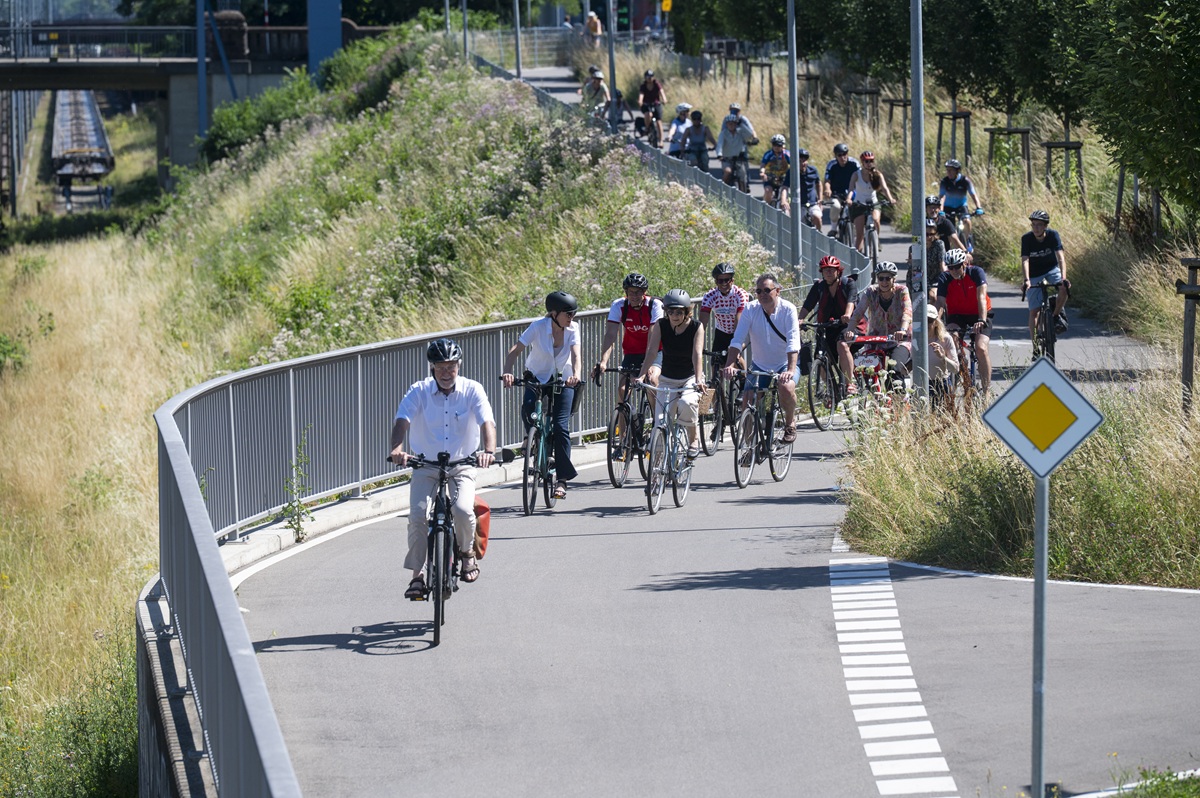 Mehrere Menschen fahren auf einem Fahrradweg Fahrrad, im Sommer