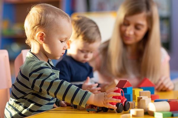 Junge Frau beim Spielen mit zwei kleinen Kindern
