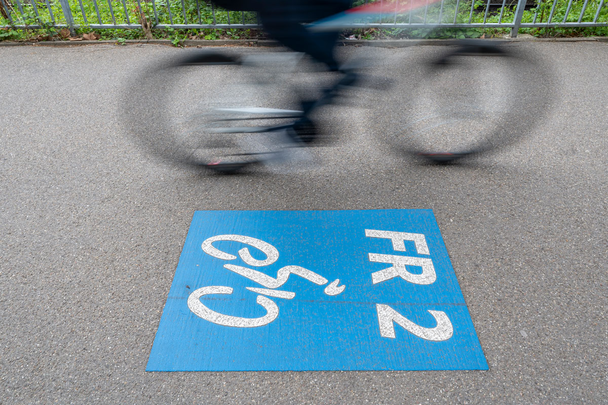 FR2 steht auf der dem Fahrradweg mit blauer Umrandung, Fahrrad fährt im Hintergrund