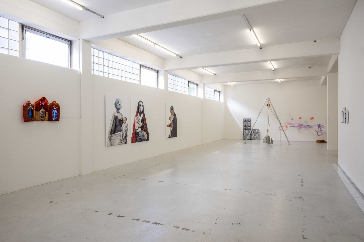 Ausstellungsansicht "Mythen von Müttern ..." 3 Videos als Tryptychon-Hausalter gestaltet (Hannah Kindler), 3 bearbeitete Fotos mit Darstellungen von Madonna mit Kind, die sich zu Robotern hin entwickeln (Sara-Lena Möllenkamp), schwerer Stein, der in einer Konstruktion hängt (Milena Naef)