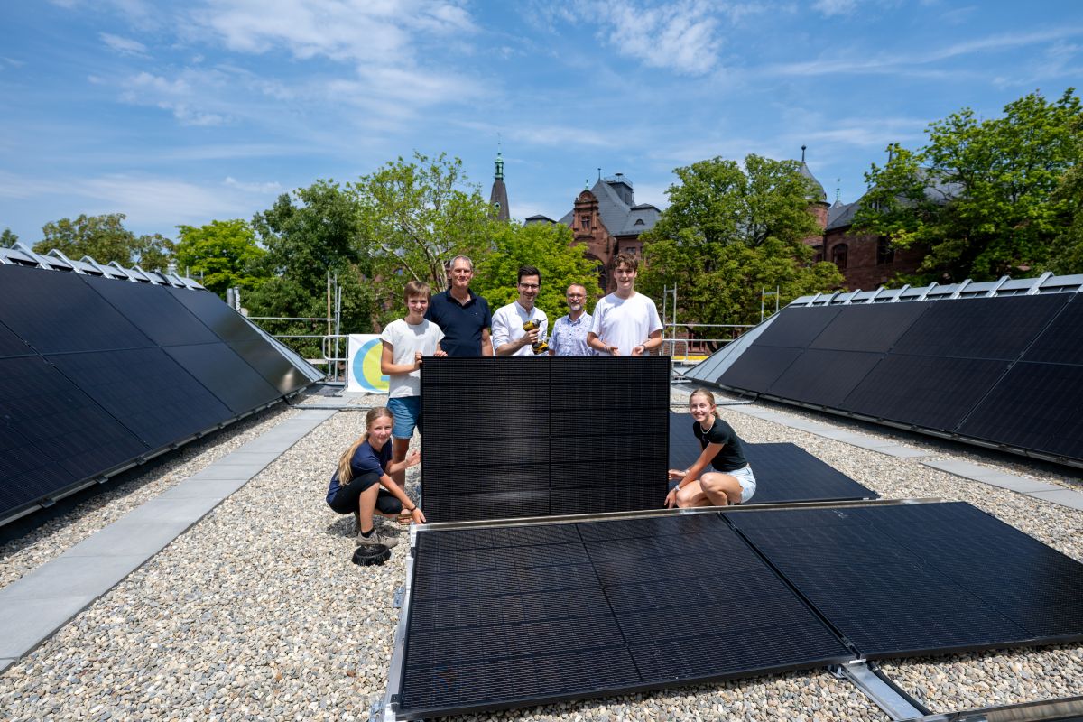 Engagierte der Klima-AG und Oberbürgermeister Martin Horn halten das letzte PV-Modul auf dem Dach des Friedrich-Gymnasiums.