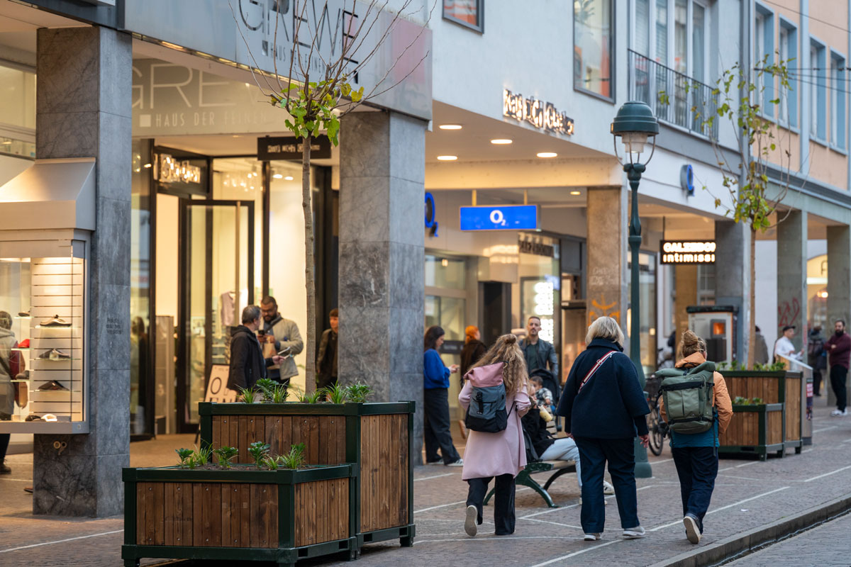 Mehrere Personen laufen durch die Kaiser-Joseph-Straße mit Bauminseln 