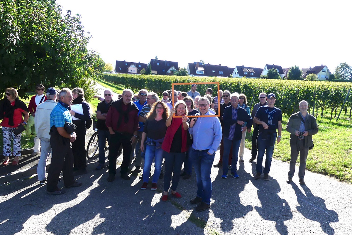 Gruppenfoto vor Weinreben mit einer Ortschaft im Hintergrund
