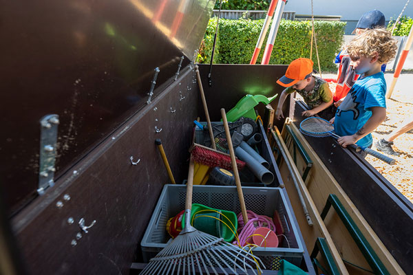 Kinder stehen neben einer Spielekiste mit Spielzeug