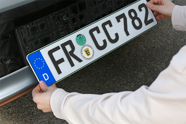 Frau installiert das Fahrzeugkennzeichen draußen, Nahaufnahme