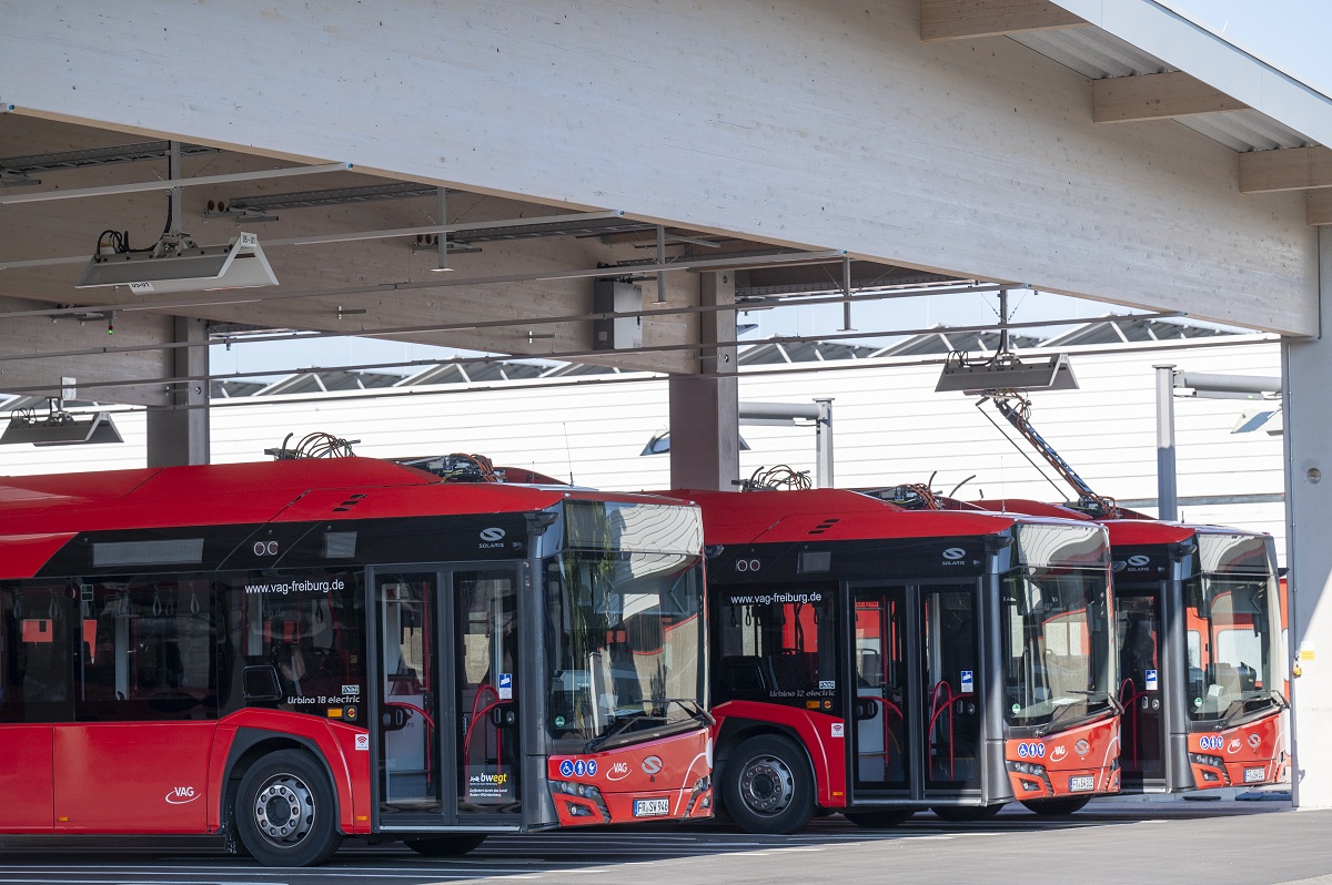 Drei rote Busse parken in einer Reihe.