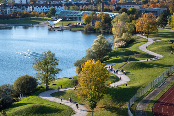Blick auf den Seepark: links Flückigersee, rechts Grünfläche mit Menschen